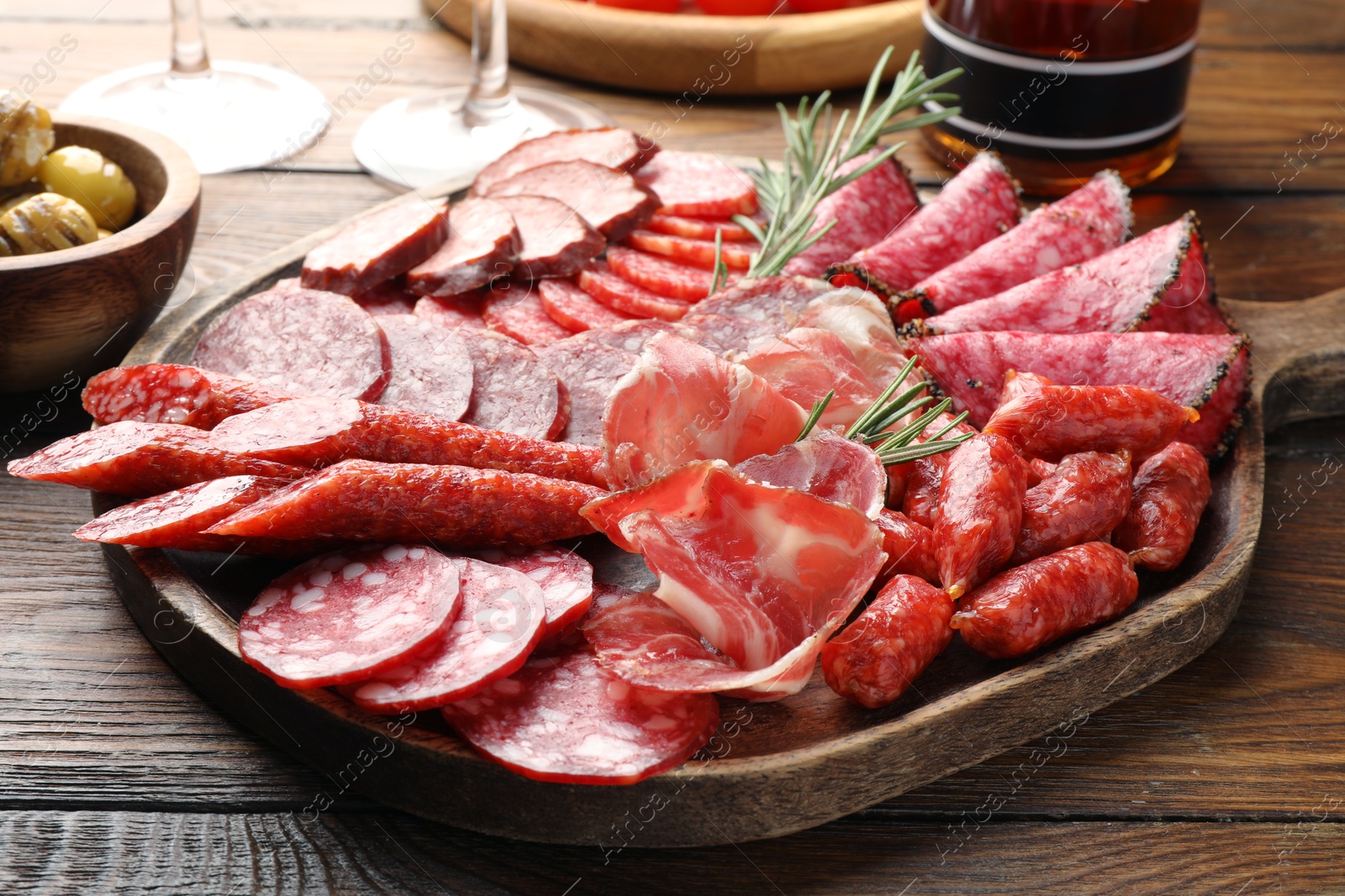 Photo of Different smoked sausages slices served on wooden table closeup