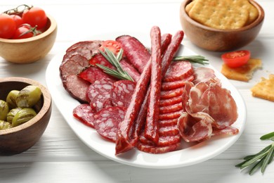 Different smoked sausages slices served on white wooden table, closeup