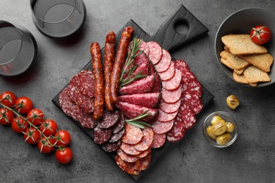 Different smoked sausages slices served on grey table, flat lay