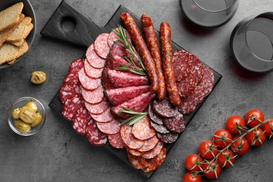 Different smoked sausages slices served on grey table, flat lay