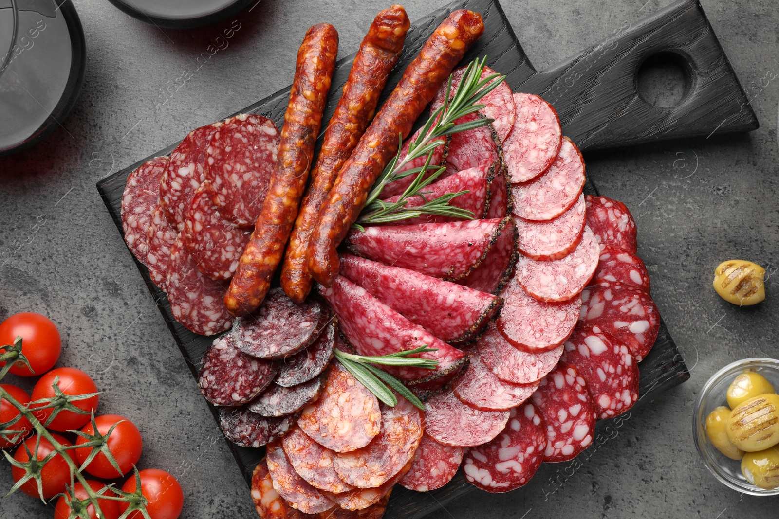 Photo of Different smoked sausages slices served on grey table, flat lay