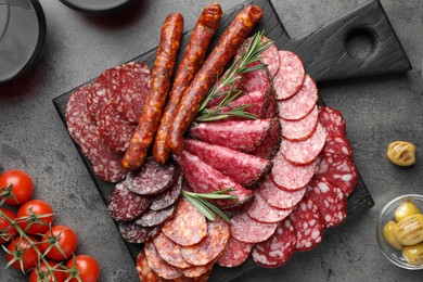 Photo of Different smoked sausages slices served on grey table, flat lay