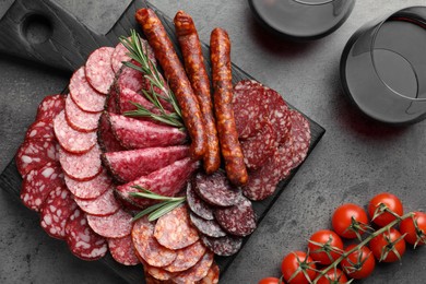 Different smoked sausages slices served on grey table, flat lay