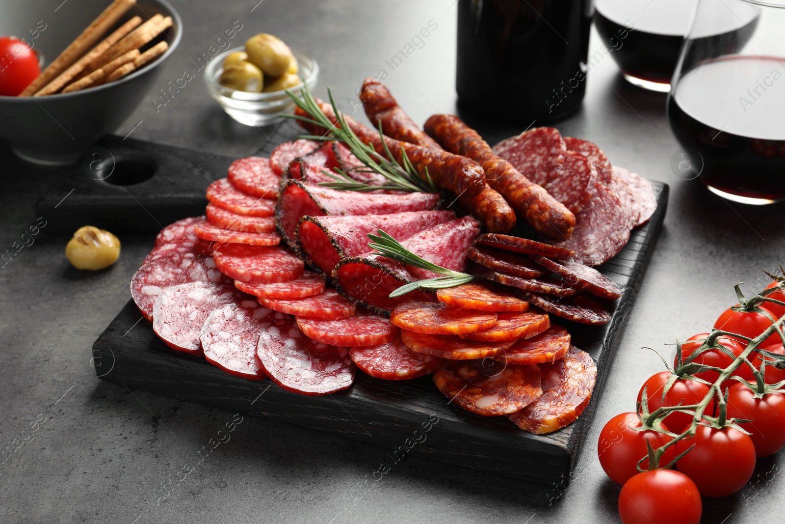 Photo of Different smoked sausages slices served on grey table, closeup