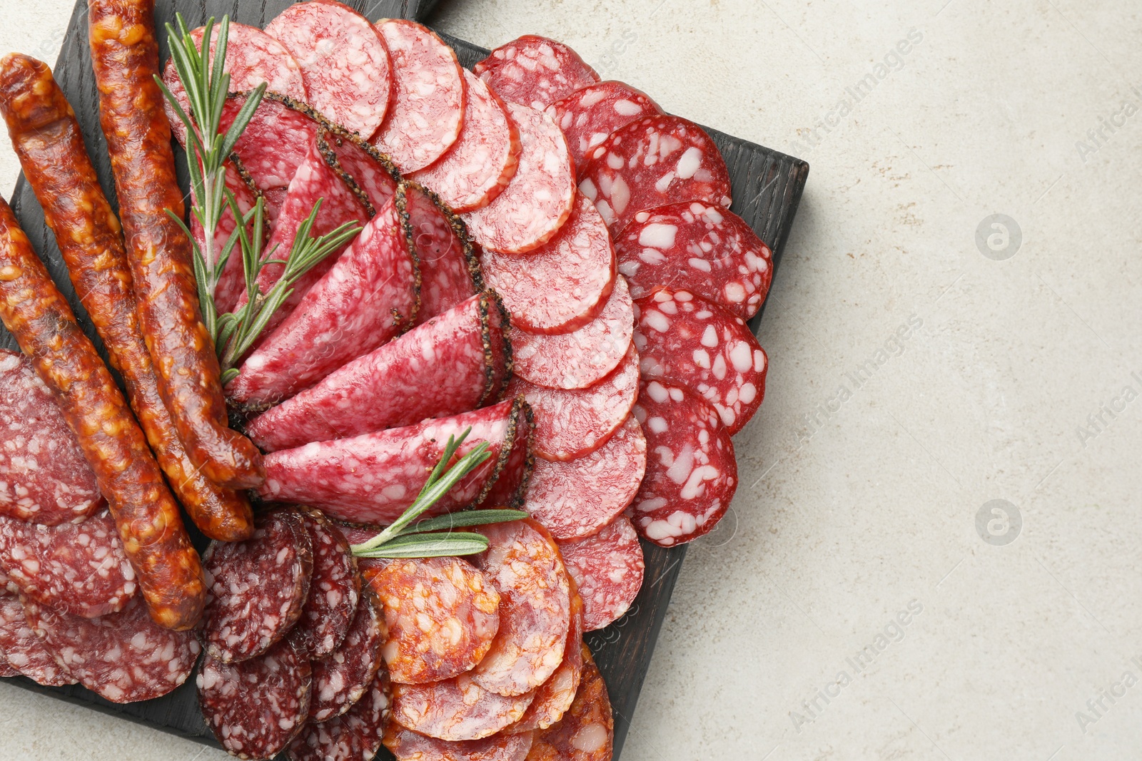 Photo of Different smoked sausages slices served on light table, top view