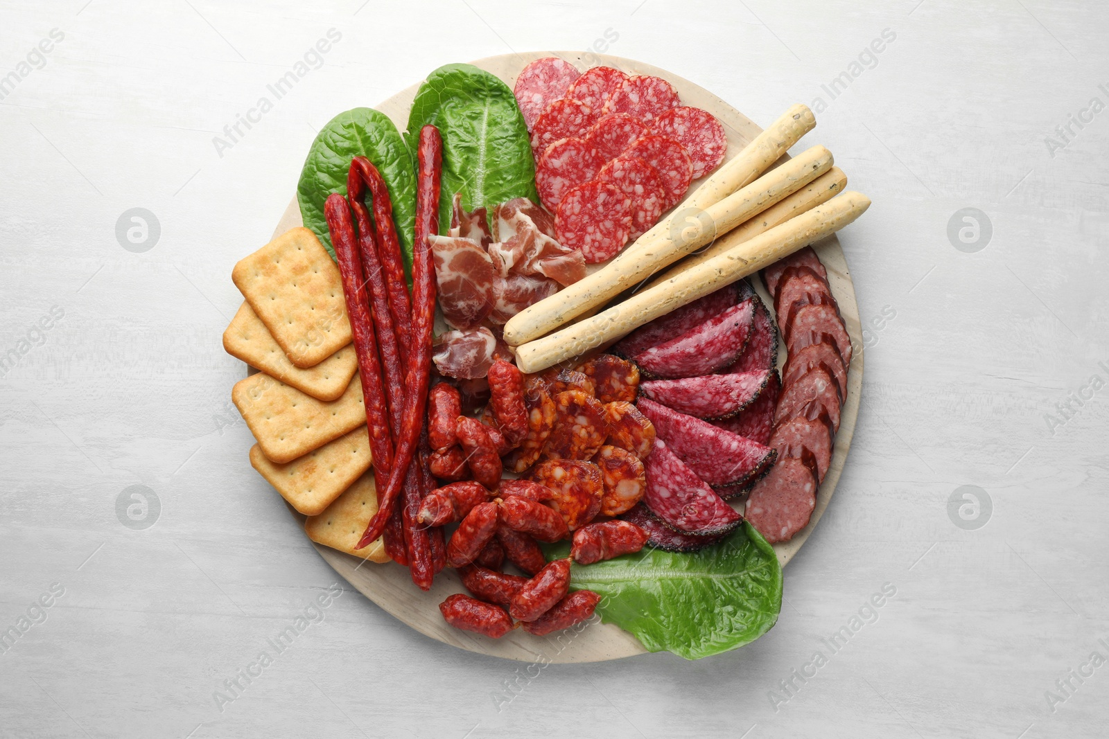 Photo of Different smoked sausages and other snacks on white table, top view