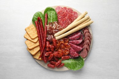 Different smoked sausages and other snacks on white table, top view