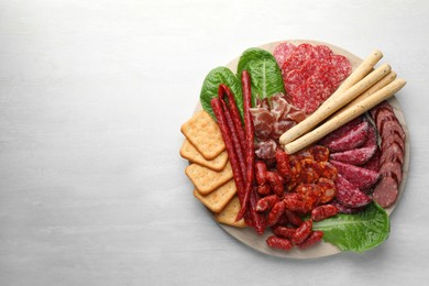 Photo of Different smoked sausages and other snacks on white table, top view. Space for text