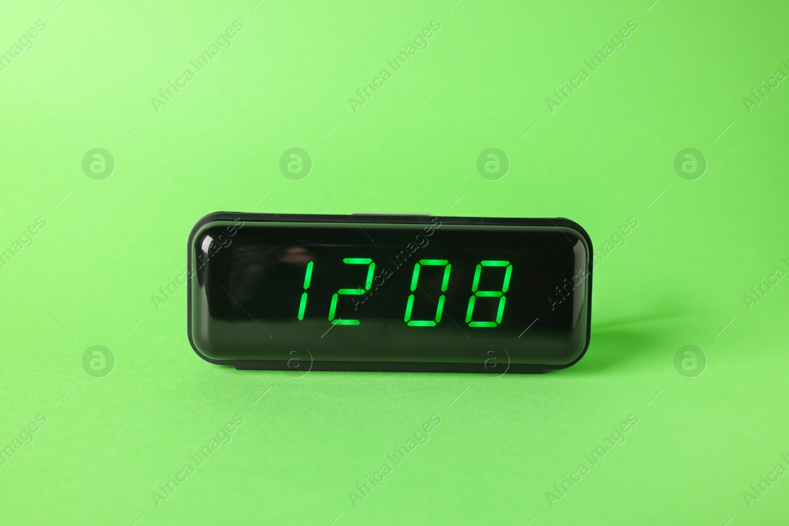Digital alarm clock showing 12:08 o'clock on green background Photo of Digital alarm clock showing 12:08 o'clock on green background