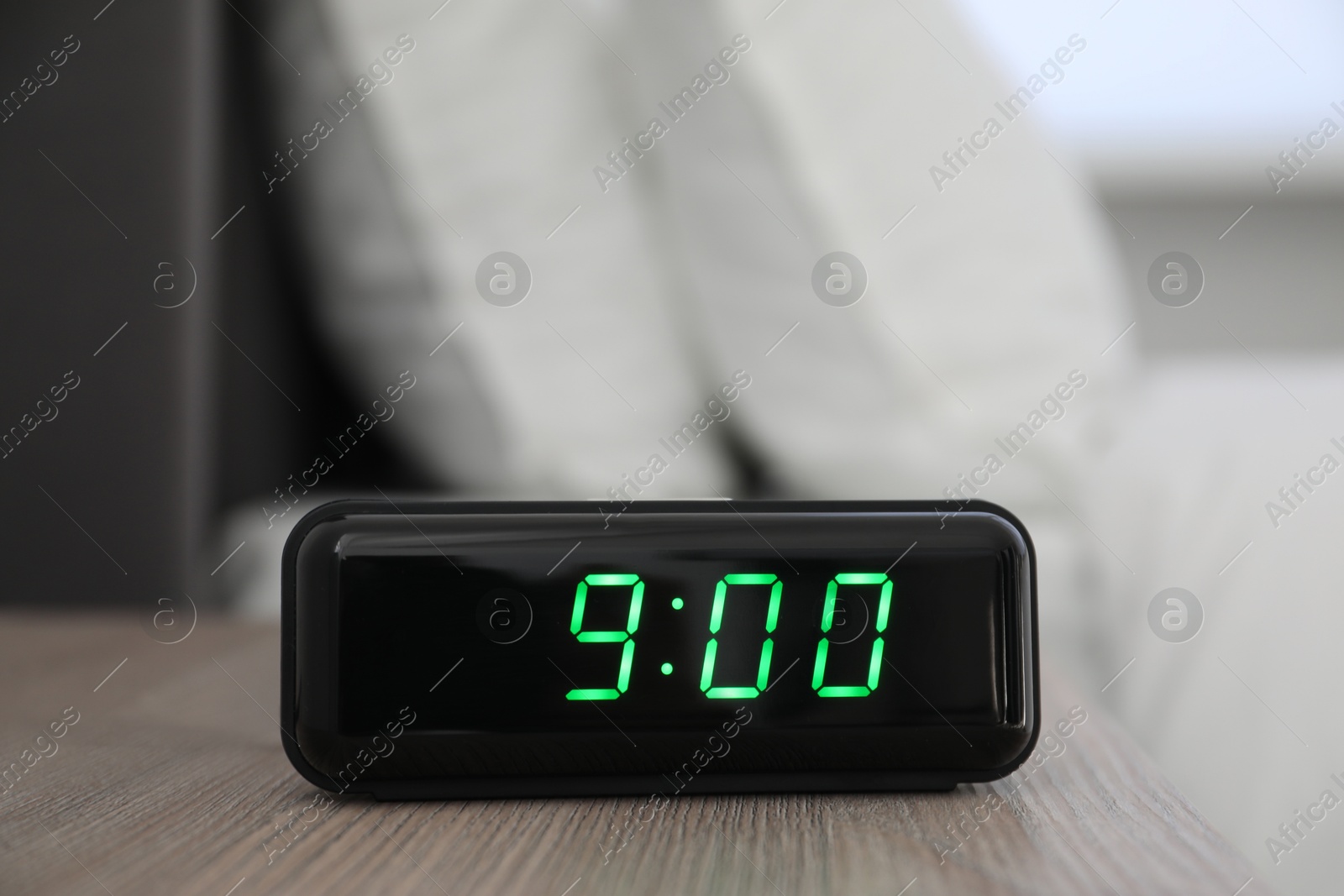 Digital alarm clock showing 9:00 o'clock on bedside table indoors Photo of Digital alarm clock showing 9:00 o'clock on bedside table indoors