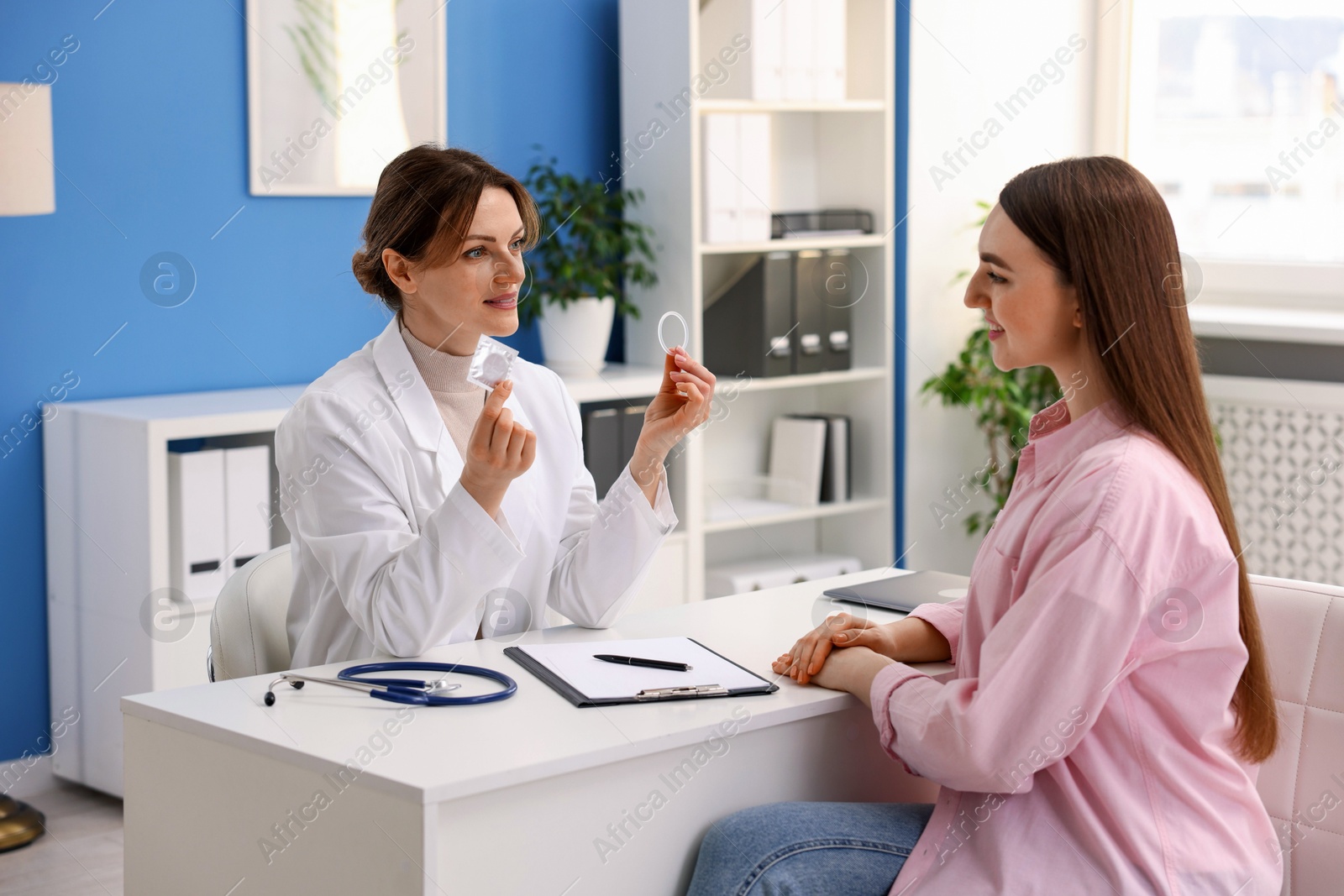 Photo of Gynecologist showing different contraceptive products to woman in clinic