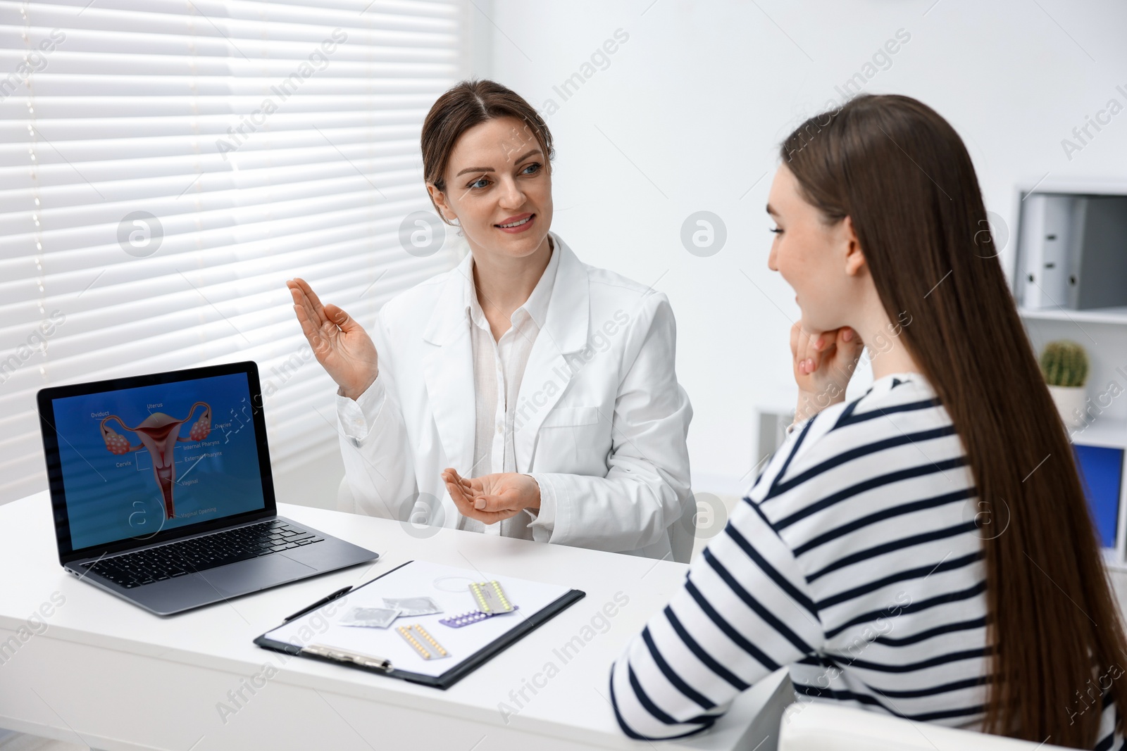 Photo of Contraception. Gynecologist showing image of female reproductive system to woman in clinic