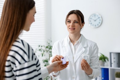 Photo of Gynecologist showing different contraceptive products to woman in clinic