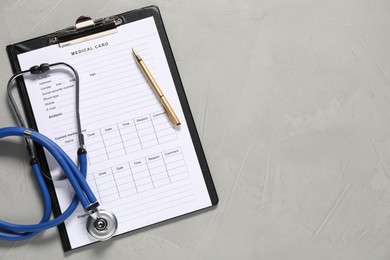 Photo of Medical card form, pen and stethoscope on grey textured table, flat lay. Space for text