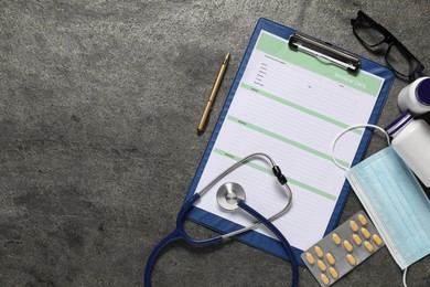 Photo of Flat lay composition with medical card form, pills and stethoscope on grey textured table. Space for text