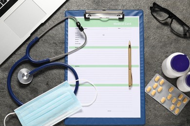 Photo of Flat lay composition with medical card form, pills and stethoscope on grey textured table