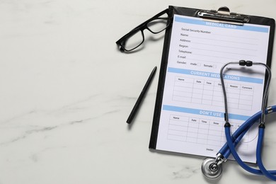 Photo of Medical card form, pen, glasses and stethoscope on white marble table, flat lay. Space for text