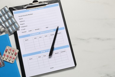 Photo of Medical card form, pen and pills on white marble table, flat lay. Space for text