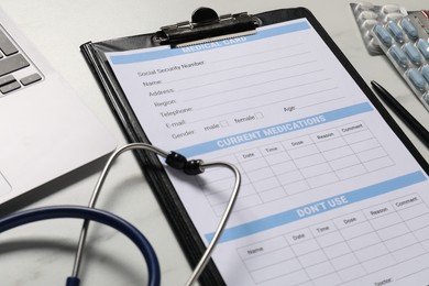 Photo of Medical card form, stethoscope and pills on white table, closeup