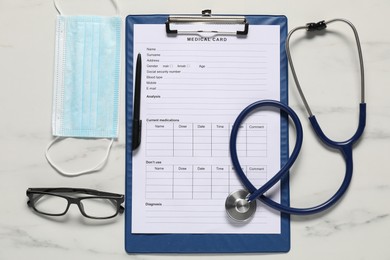 Photo of Medical card form, pen, protective mask and stethoscope on white marble table, flat lay