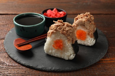 Photo of Tasty onigiri (Japanese rice balls) with tuna served on wooden table, closeup