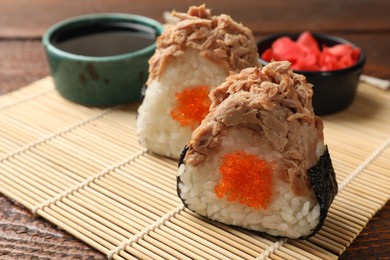 Photo of Tasty onigiri (Japanese rice balls) with tuna served on wooden table, closeup