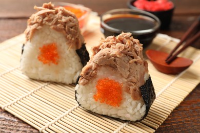 Photo of Tasty onigiri (Japanese rice balls) with tuna served on wooden table, closeup
