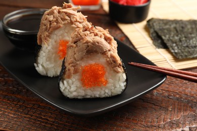 Photo of Tasty onigiri (Japanese rice balls) with tuna served on wooden table, closeup