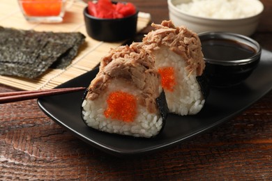 Photo of Tasty onigiri (Japanese rice balls) with tuna served on wooden table, closeup