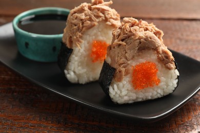 Photo of Tasty onigiri (Japanese rice balls) with tuna served on wooden table, closeup