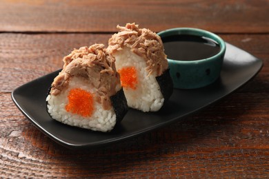Photo of Tasty onigiri (Japanese rice balls) with tuna served on wooden table, closeup