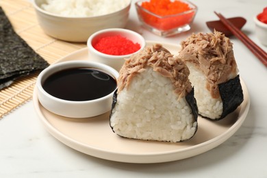 Photo of Tasty onigiri (Japanese rice balls) with tuna served on white marble table, closeup