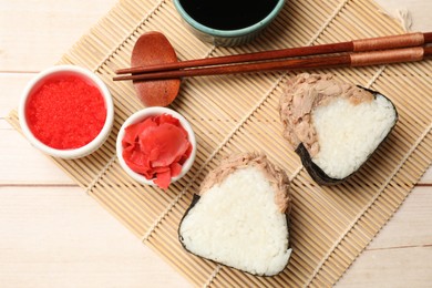 Photo of Tasty onigiri (Japanese rice balls) with tuna served on wooden table, flat lay