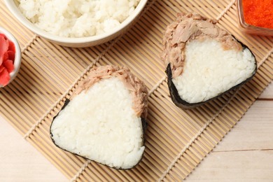 Photo of Tasty onigiri (Japanese rice balls) with tuna served on wooden table, flat lay