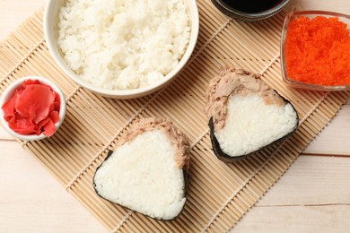 Photo of Tasty onigiri (Japanese rice balls) with tuna served on wooden table, flat lay