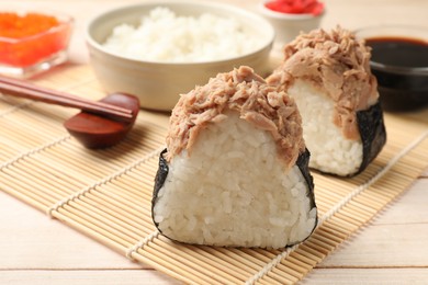 Photo of Tasty onigiri (Japanese rice balls) with tuna served on wooden table, closeup