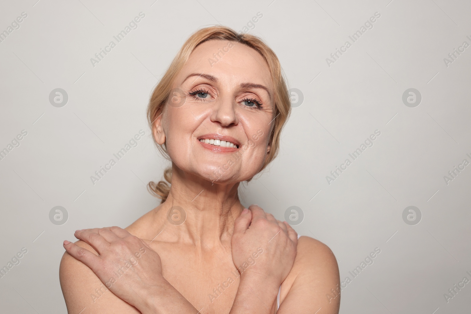 Photo of Portrait of smiling middle aged woman on grey background