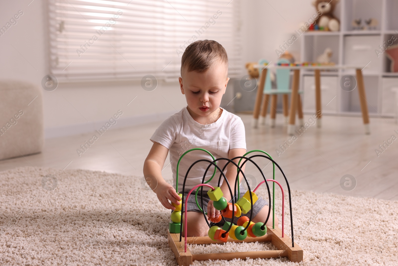 Photo of Motor skills development. Little boy playing with toy on floor at home