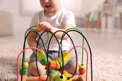 Photo of Motor skills development. Little boy playing with toy on floor at home, closeup