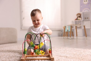 Motor skills development. Little boy playing with toy on floor at home, space for text