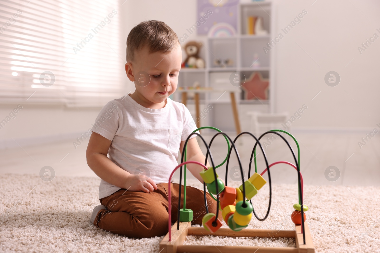 Photo of Motor skills development. Little boy playing with toy on floor at home