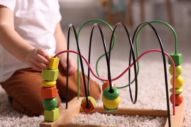 Motor skills development. Little boy playing with toy on floor at home, closeup