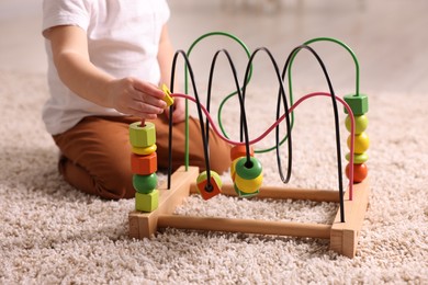 Motor skills development. Little boy playing with toy on floor at home, closeup