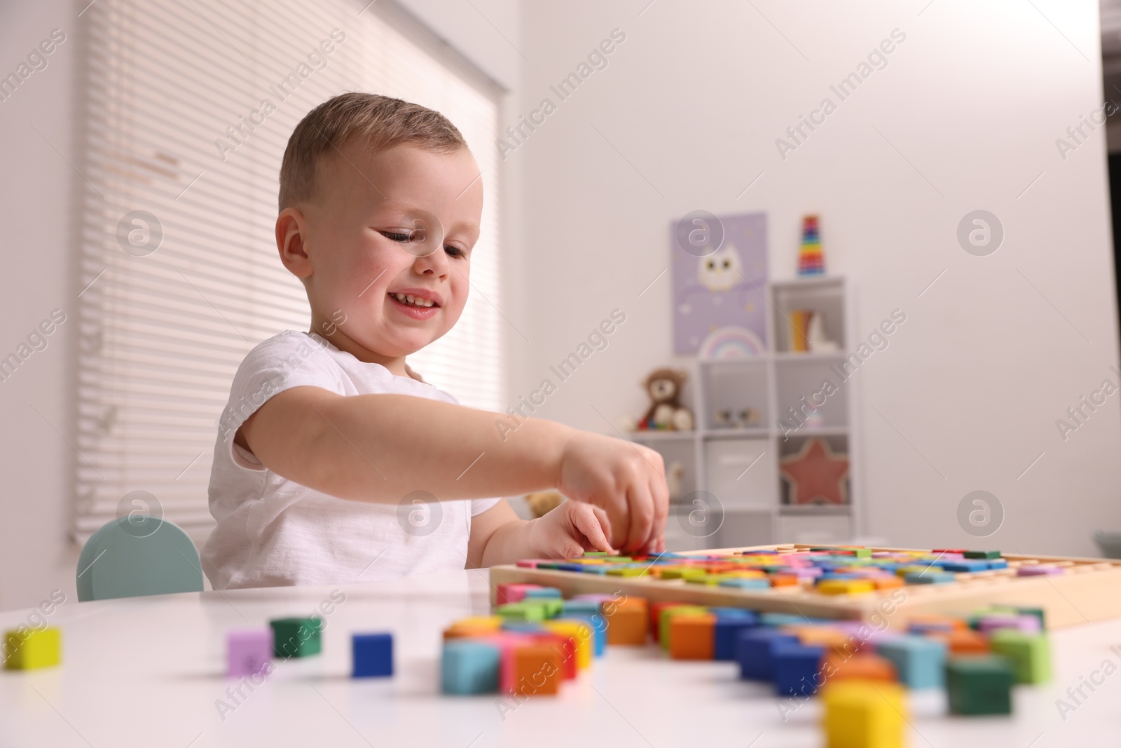 Photo of Motor skills development. Little boy playing with Times table tray indoors