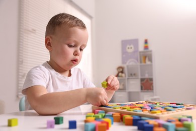 Motor skills development. Little boy playing with Times table tray indoors