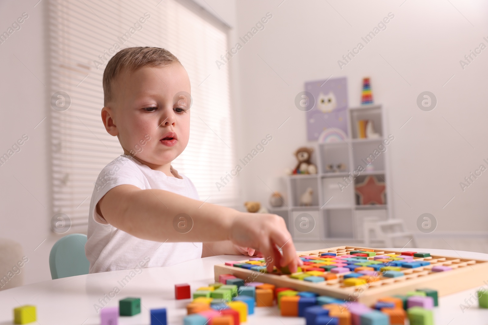 Photo of Motor skills development. Little boy playing with Times table tray indoors