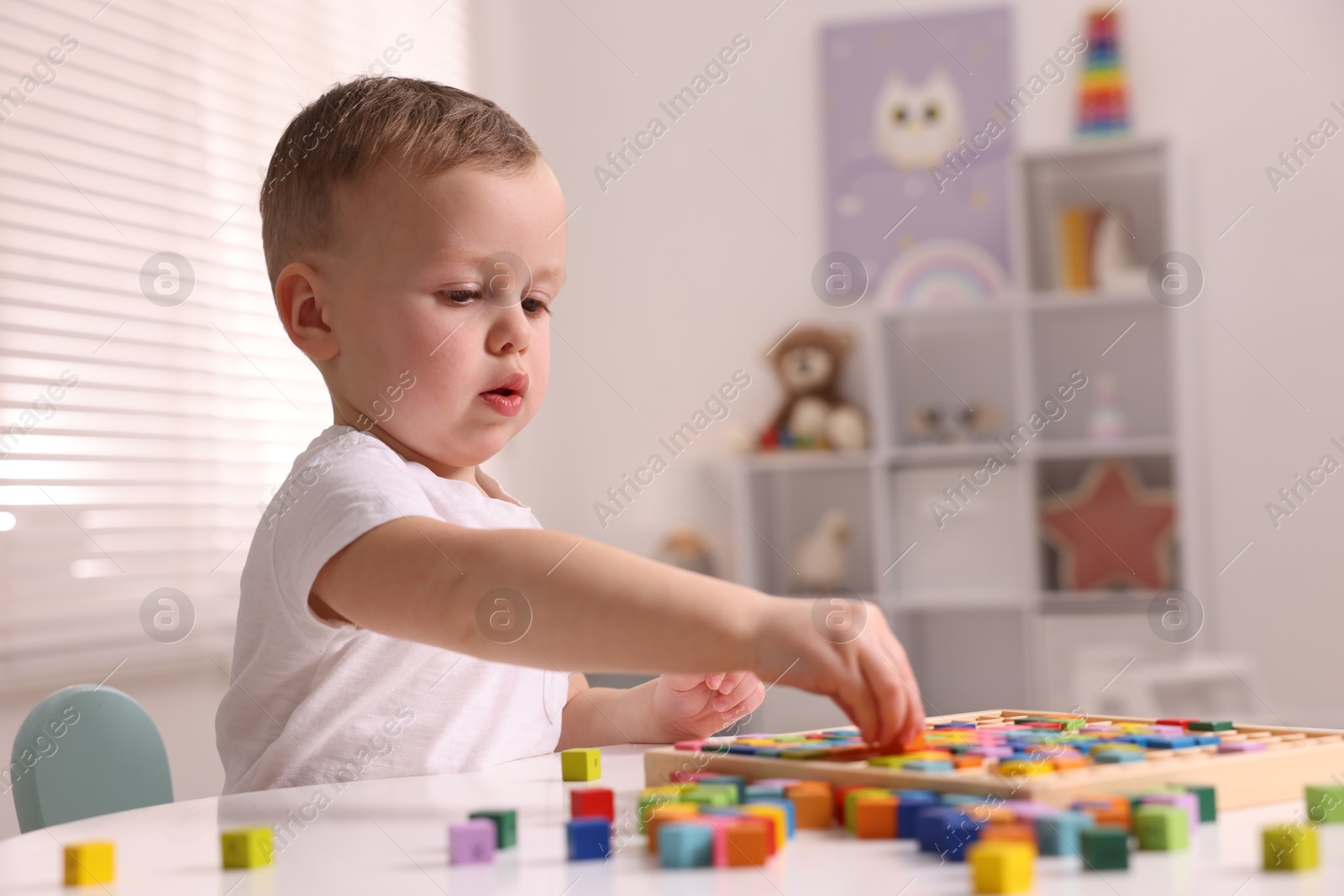 Photo of Motor skills development. Little boy playing with Times table tray indoors