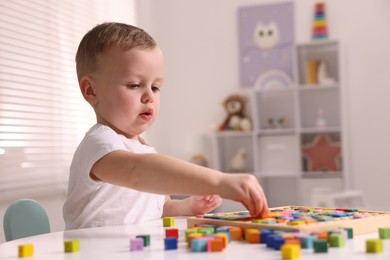 Motor skills development. Little boy playing with Times table tray indoors