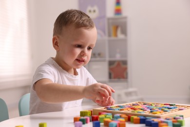 Photo of Motor skills development. Little boy playing with Times table tray indoors