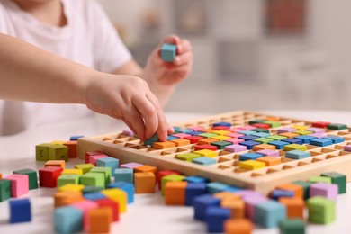 Motor skills development. Little boy playing with Times table tray indoors, closeup